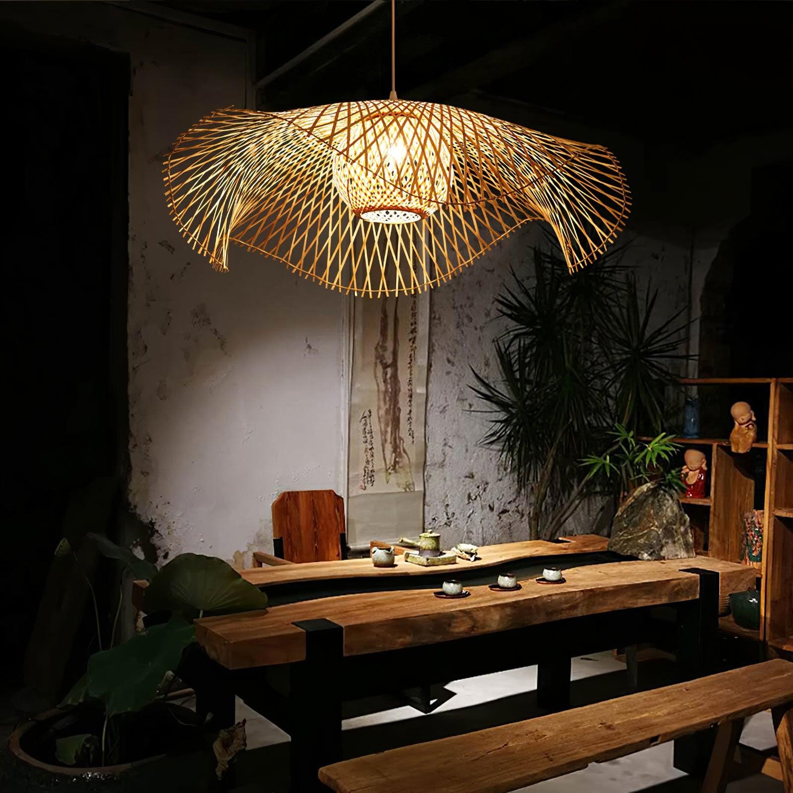 Lámpara colgante de bambú con forma de hoja de loto sobre una mesa de comedor en un interior con ambiente acogedor.