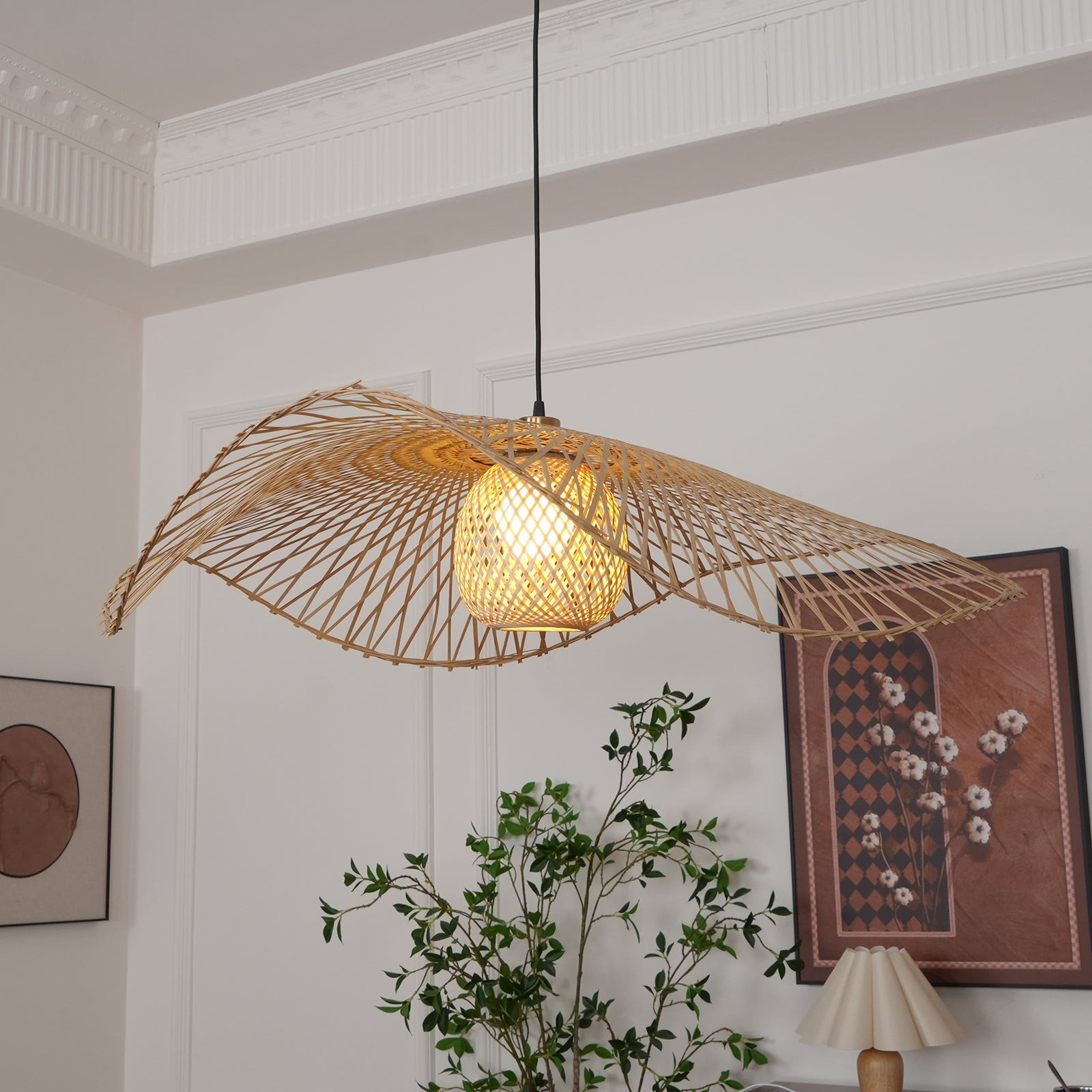 Lámpara colgante de bambú con forma de hoja de loto en una habitación luminosa con decoración vegetal.