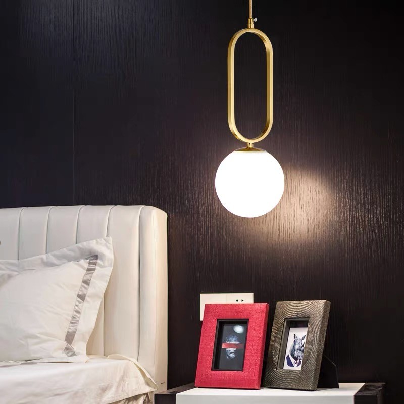 Lit oval ring pendant above a bedside table