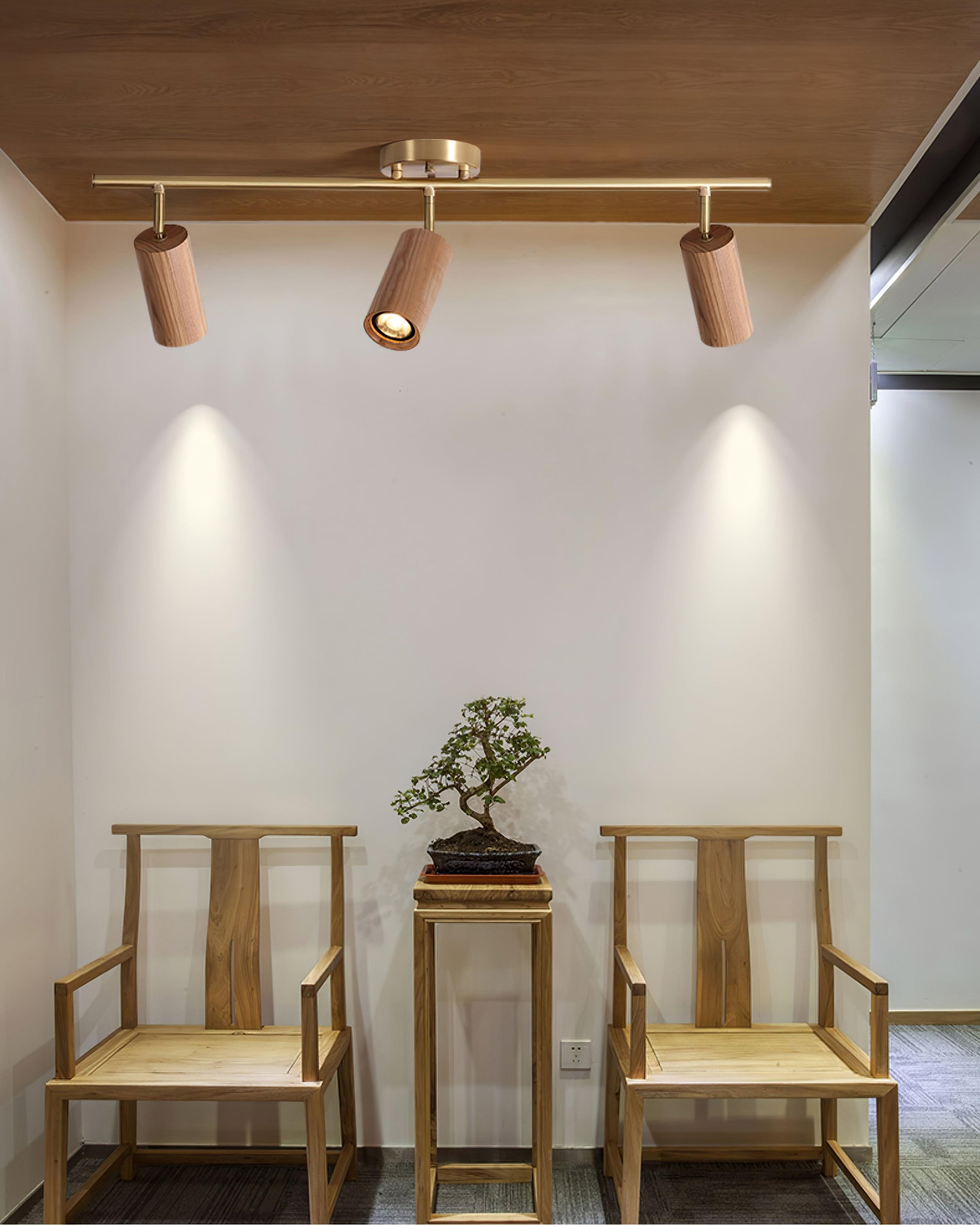 Three-head wooden track light above chairs in a warm interior
