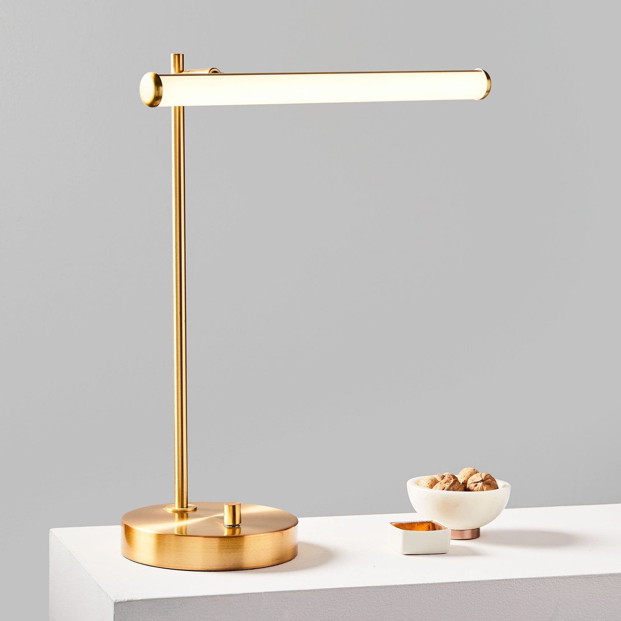 Voro bordslampa på bordsskiva med liten dekor mot en grå vägg