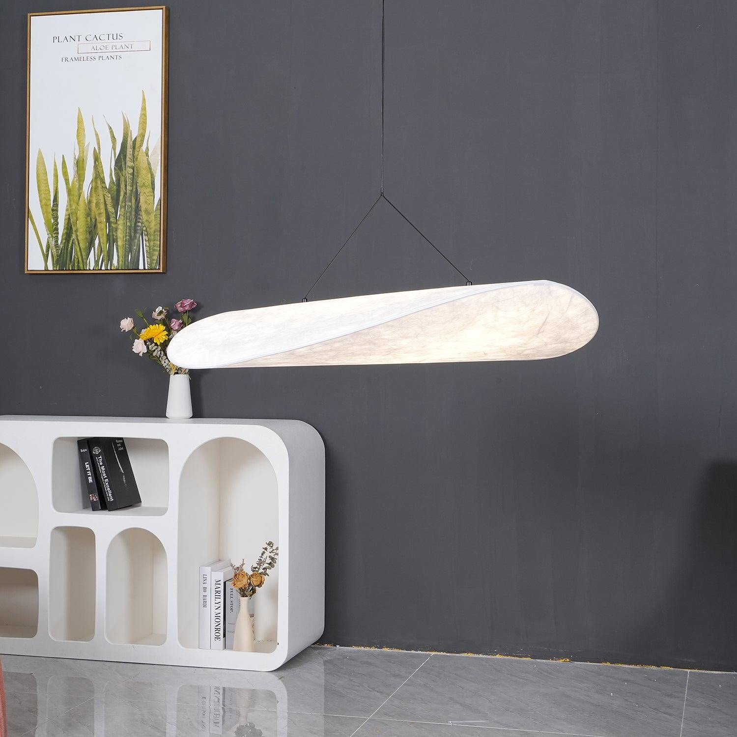 Lampa wisząca Lit TENSE na tle ciemnej ściany z meblami dla uzyskania skali