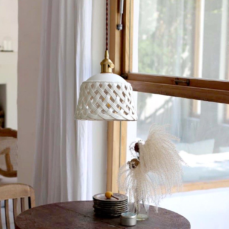 Lampada a sospensione in ceramica traforata installata sopra un tavolo vicino a una finestra