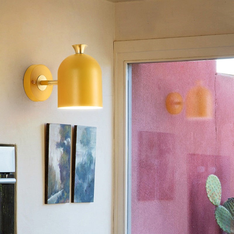 Żółta lampa ścienna makaronik zainstalowana w pobliżu grafiki na drzwiach