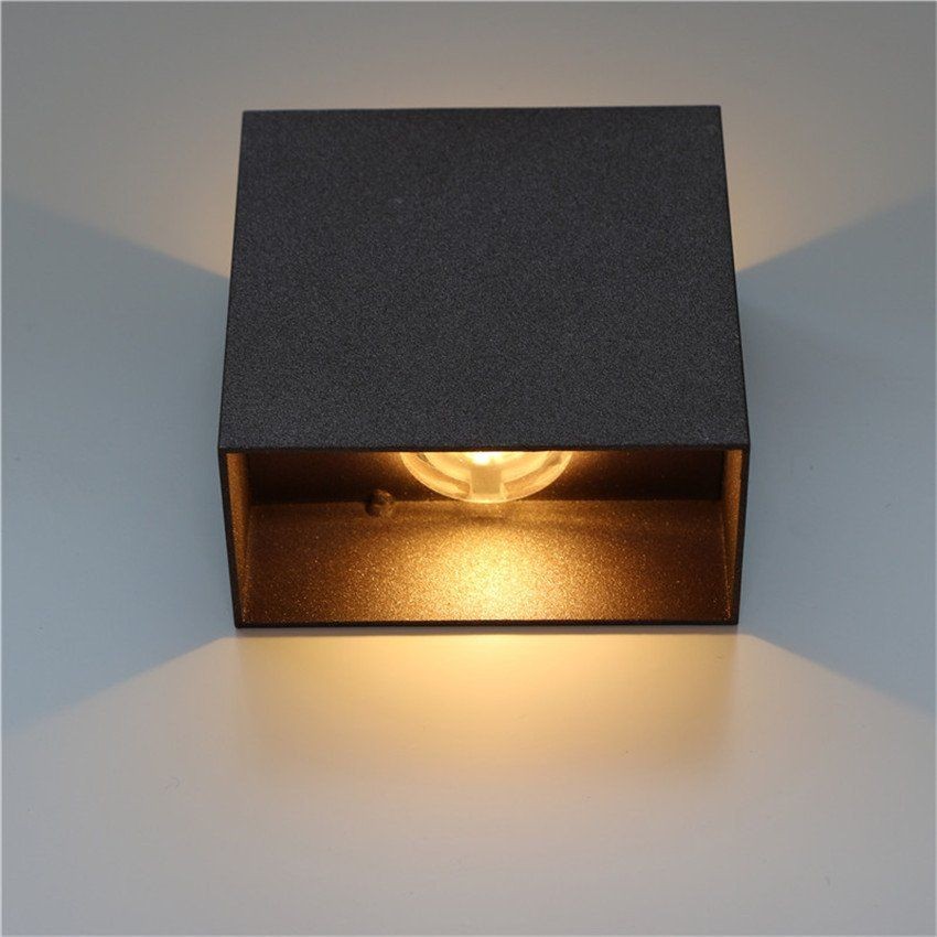Nærbilde av svart Cube LED-vegglampe som viser undersiden og lysutbytte