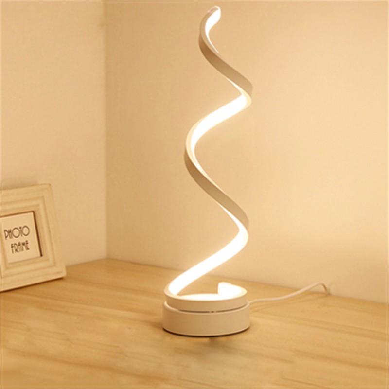 Spiralförmige, geometrische Schreibtischlampe, die auf einer Tischplatte leuchtet