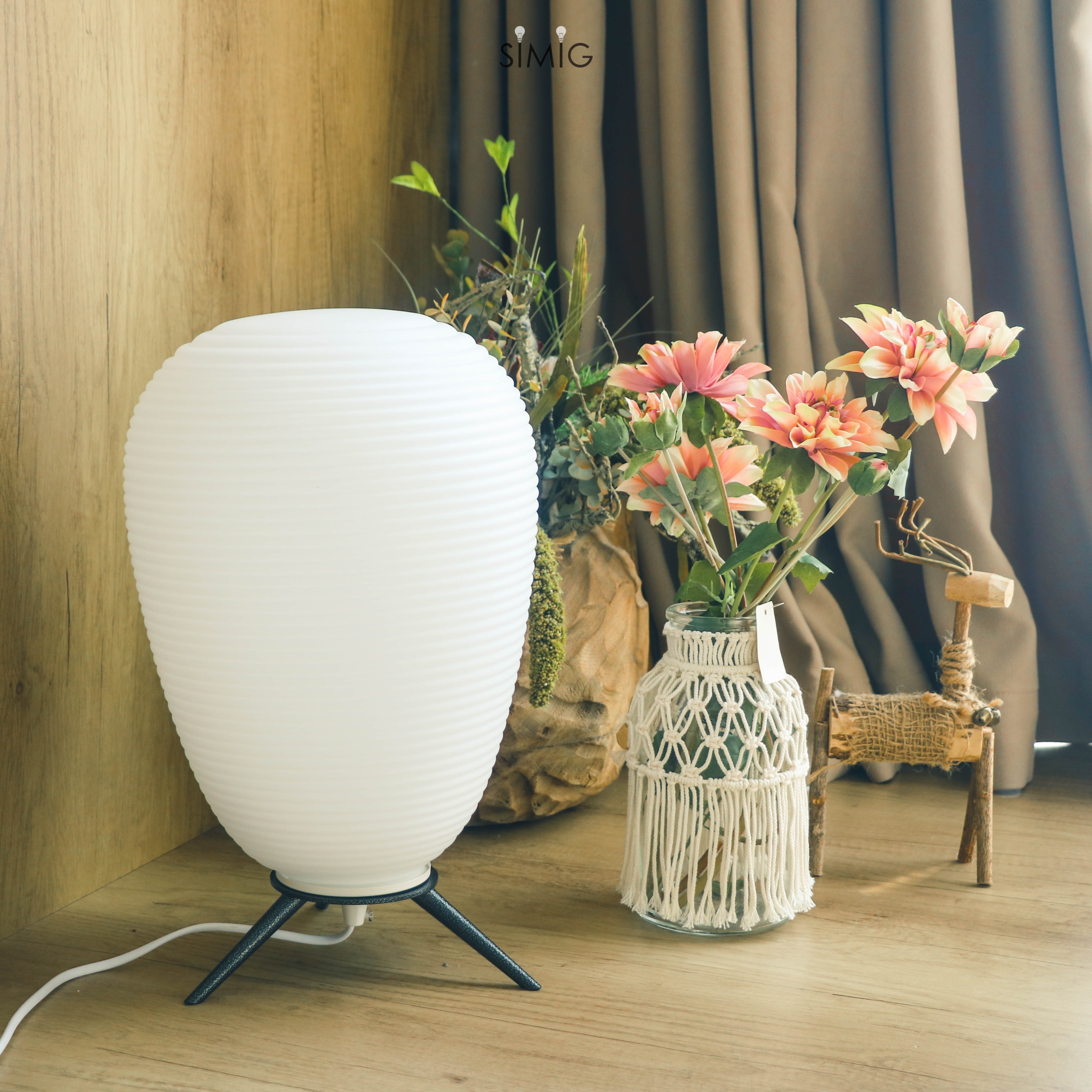 Lampada posizionata accanto a un vaso di fiori in un interno decorato.