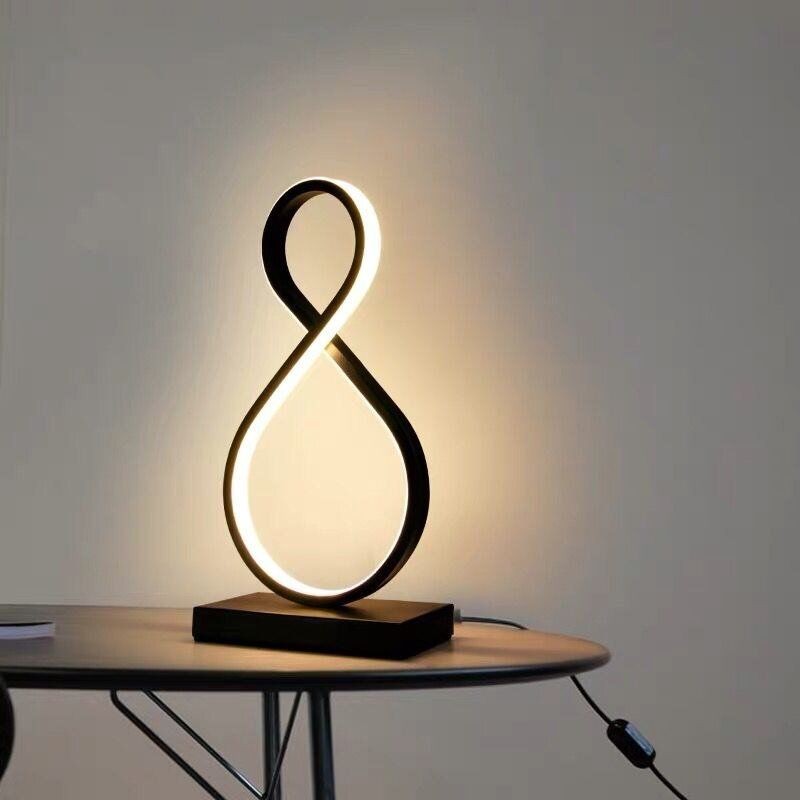 Geometrische Schreibtischlampe in Form einer Acht auf einem Tisch mit Wandbeleuchtung