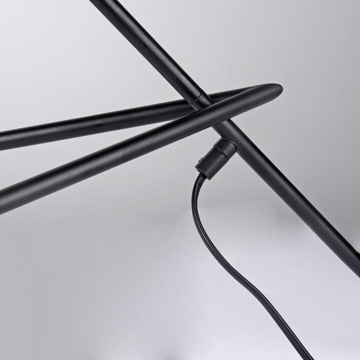 Primer plano de la estructura de la lámpara trípode de metal negro y detalle de la unión.