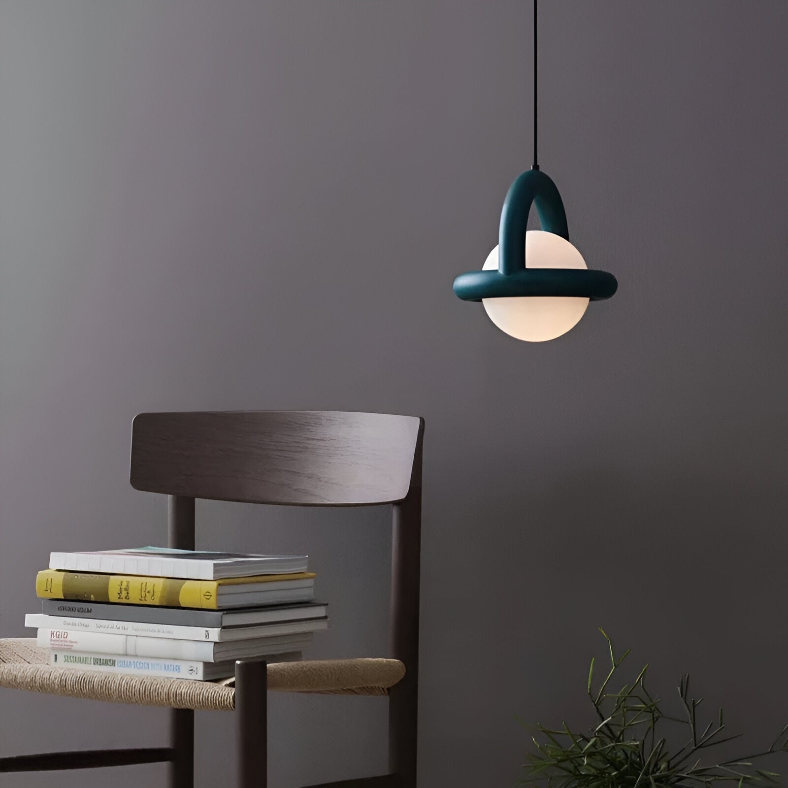 Lampa wisząca Nordic Cory nad krzesłem i książkami