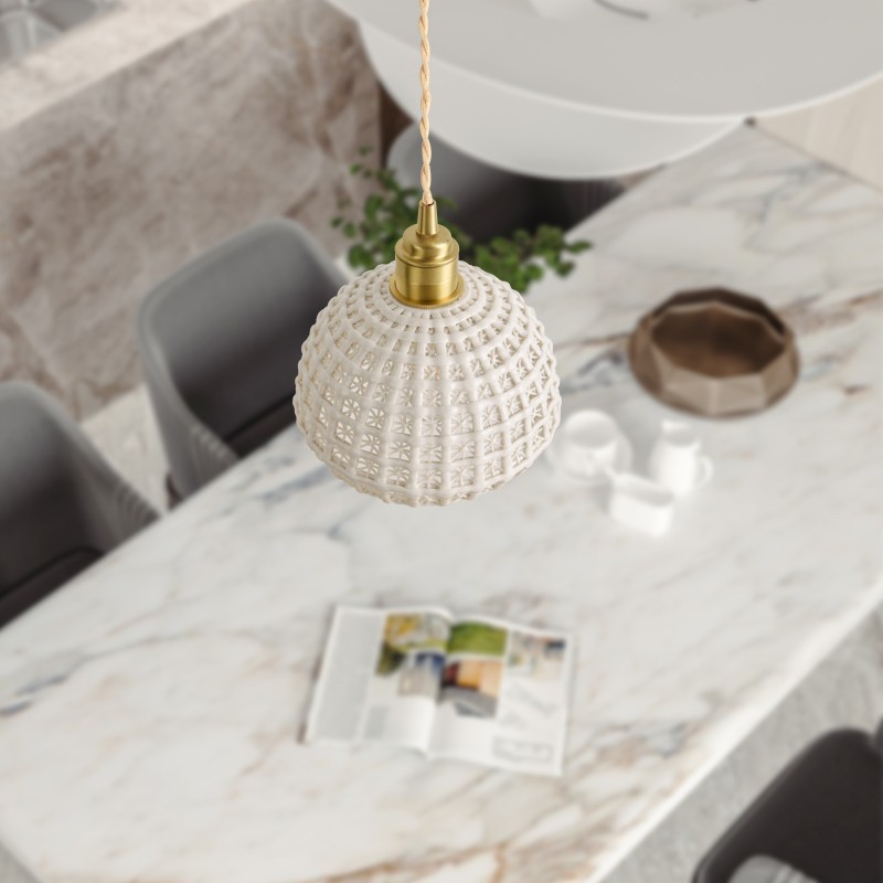 Ceramiczna lampa wisząca z koszem kwiatów nad marmurowym blatem