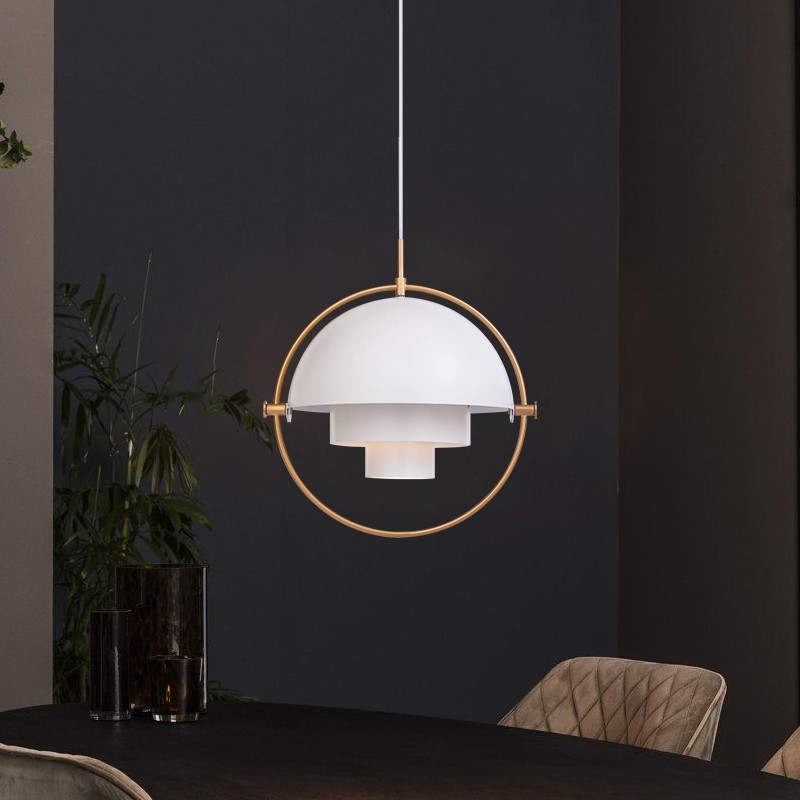 Biała i mosiężna lampa wisząca rozświetlona w ciemnej scenerii jadalni