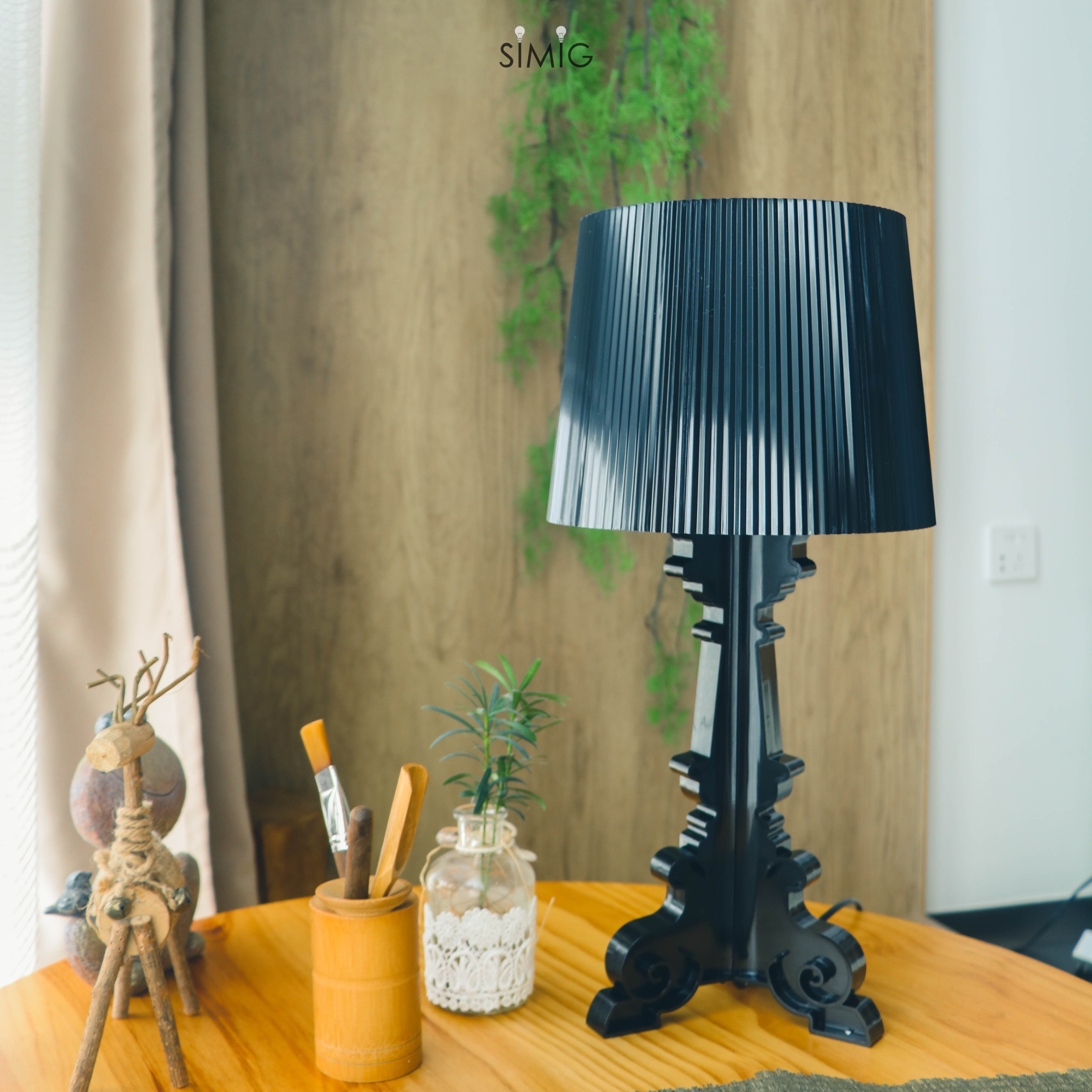 Lámpara Bourgie negra sobre una mesa con objetos decorativos.