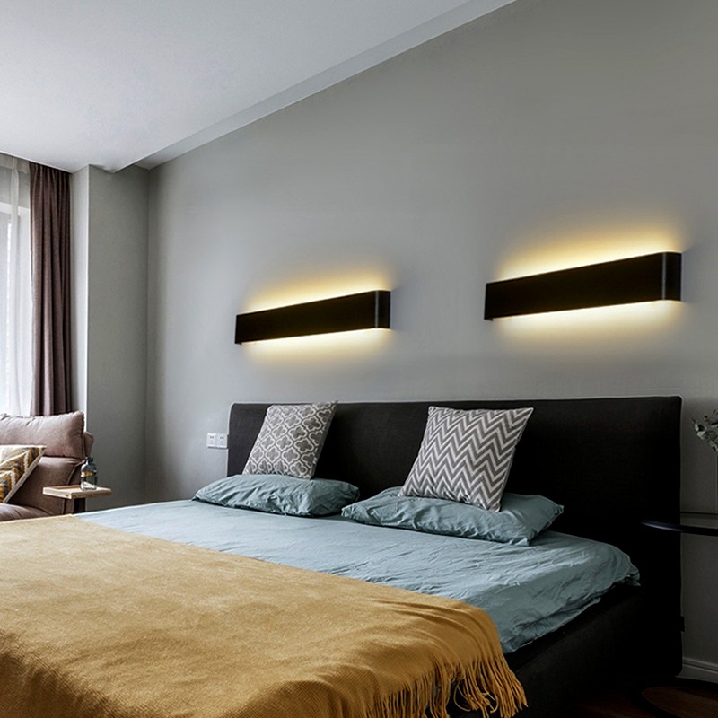 Due eleganti lampade da parete a LED SIMIG nere, posizionate sopra un letto.