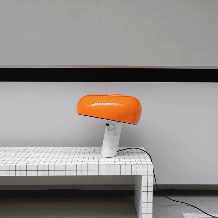 Pomarańczowa, zakrzywiona marmurowa lampa stołowa na minimalistycznej ławce wyłożonej kafelkami