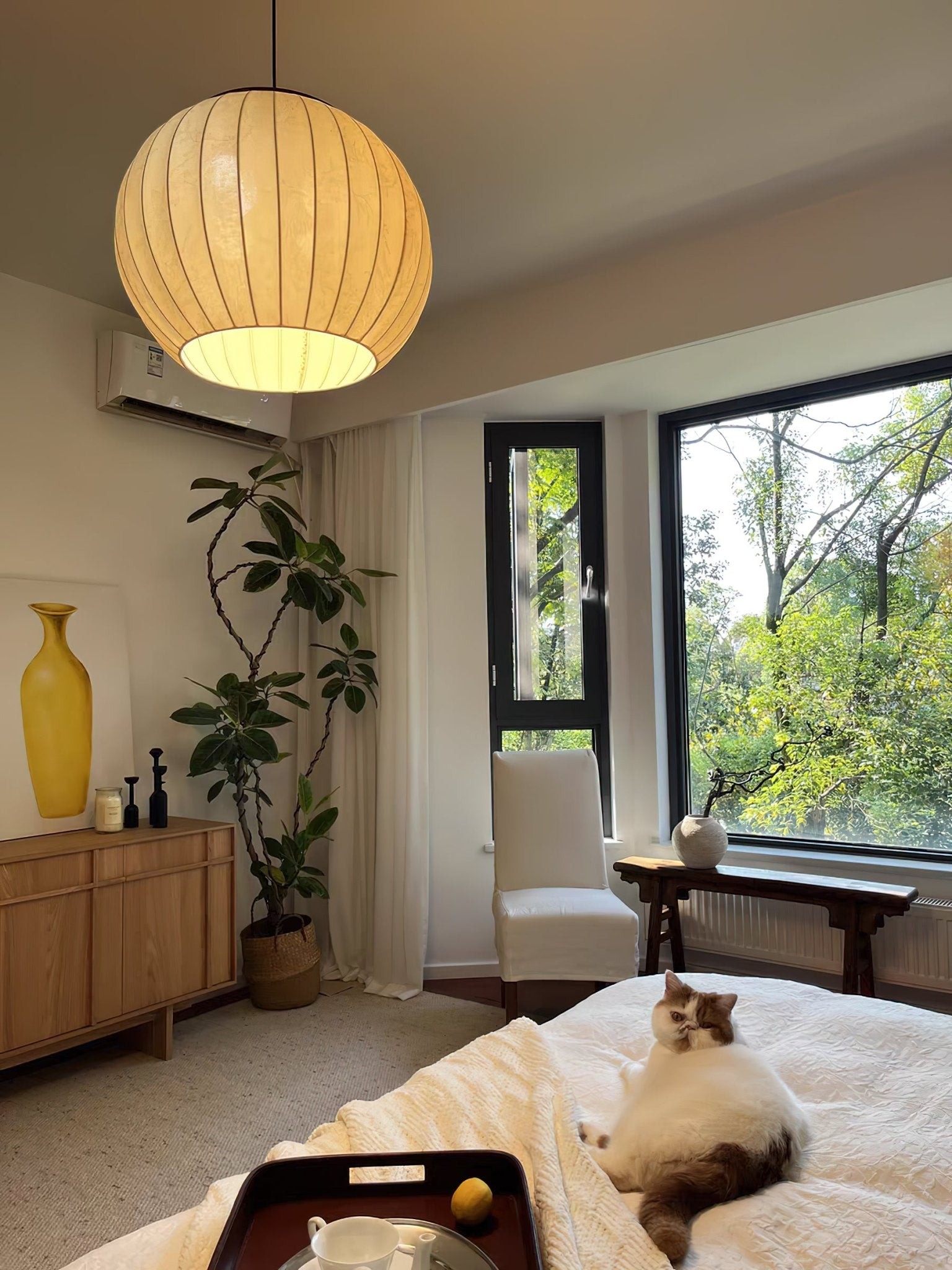 Illuminated fabric lantern pendant in a warm bedroom interior