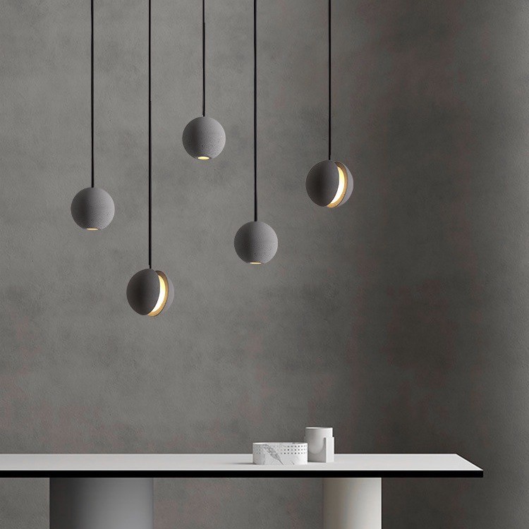 Wiele lamp wiszących nad minimalistycznym stołem i teksturowaną ścianą
