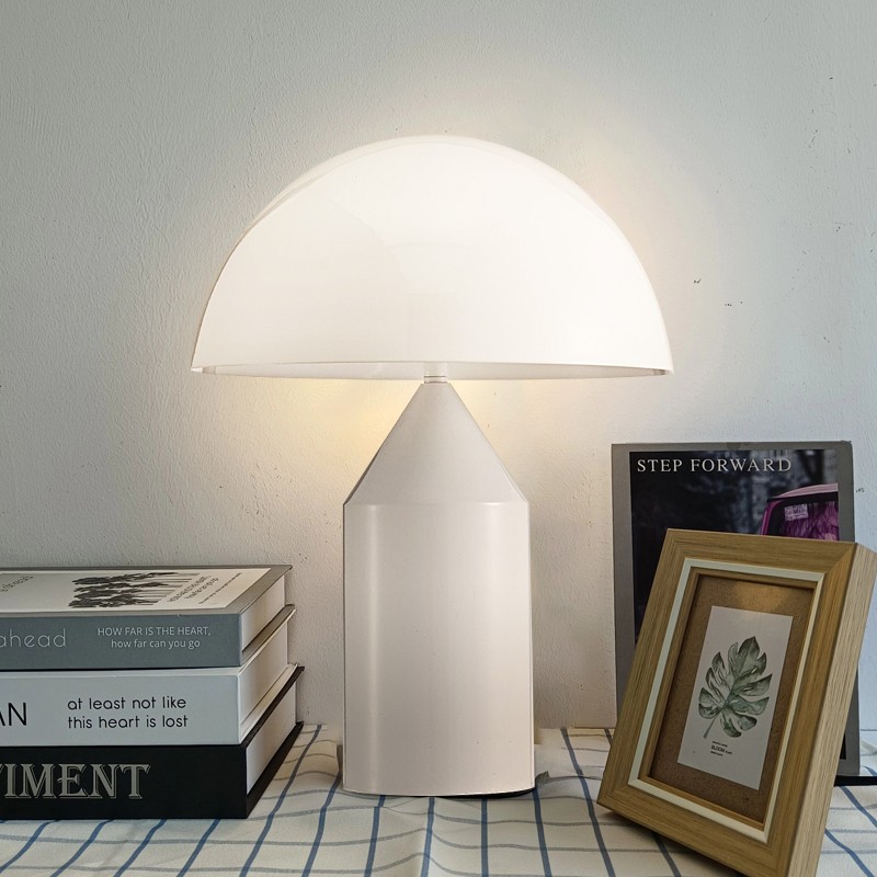 Biała lampa grzybkowa zapalona na blacie z dekoracją w ramce