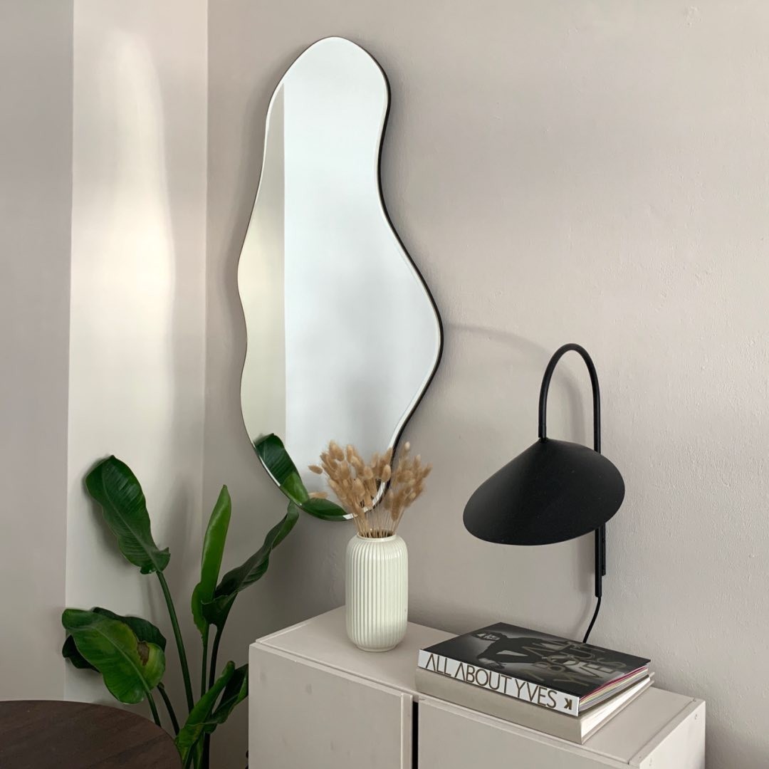 Black wall lamp beside mirror and tabletop decor