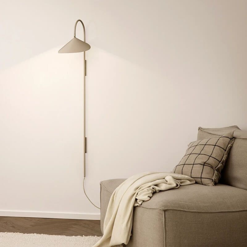 Cashmere wall lamp illuminated beside sofa or bed with mount and cord visible