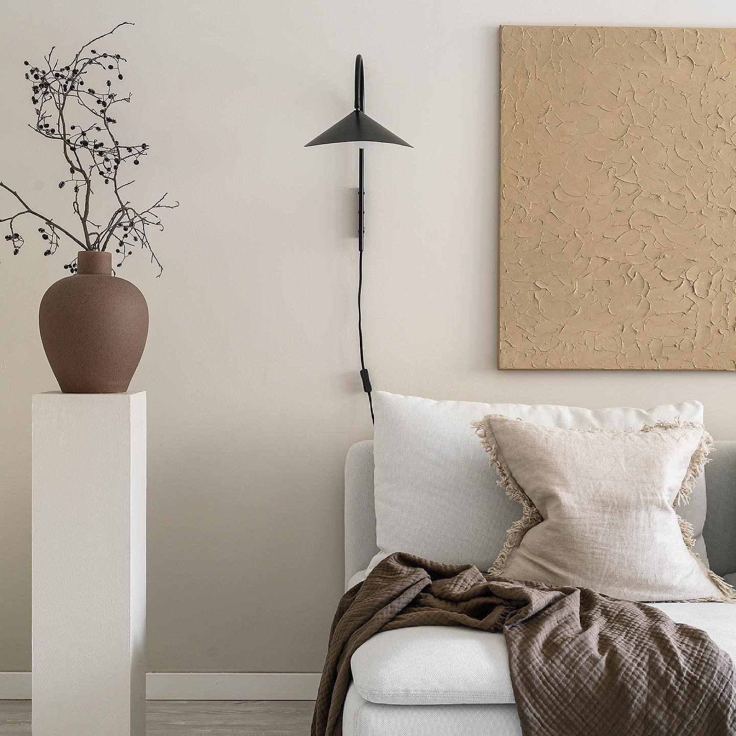 Black leaf-shaped wall lamp installed above a bedroom seating area