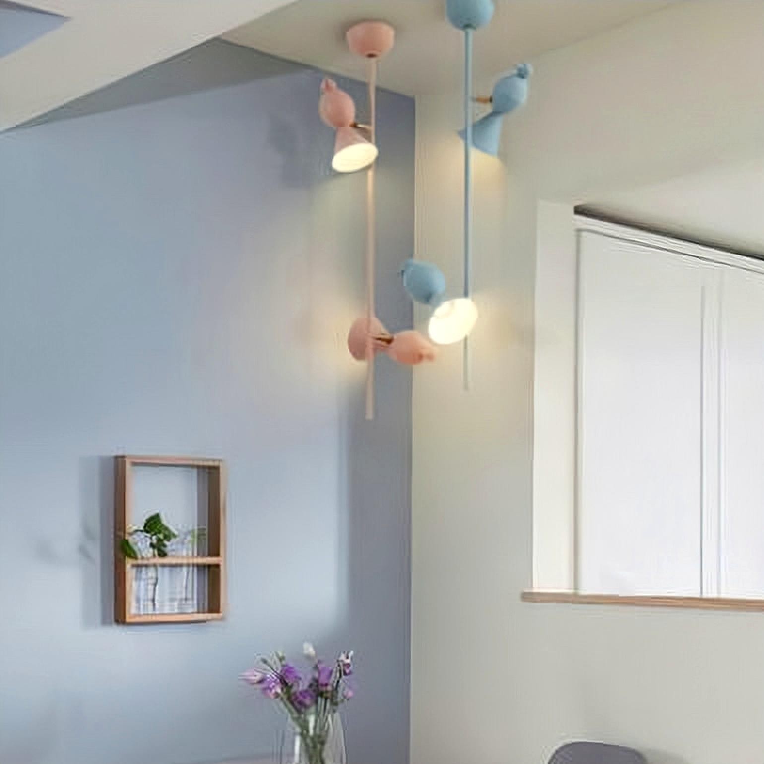Lámparas colgantes con forma de pájaro azules y rosas cerca de una ventana.