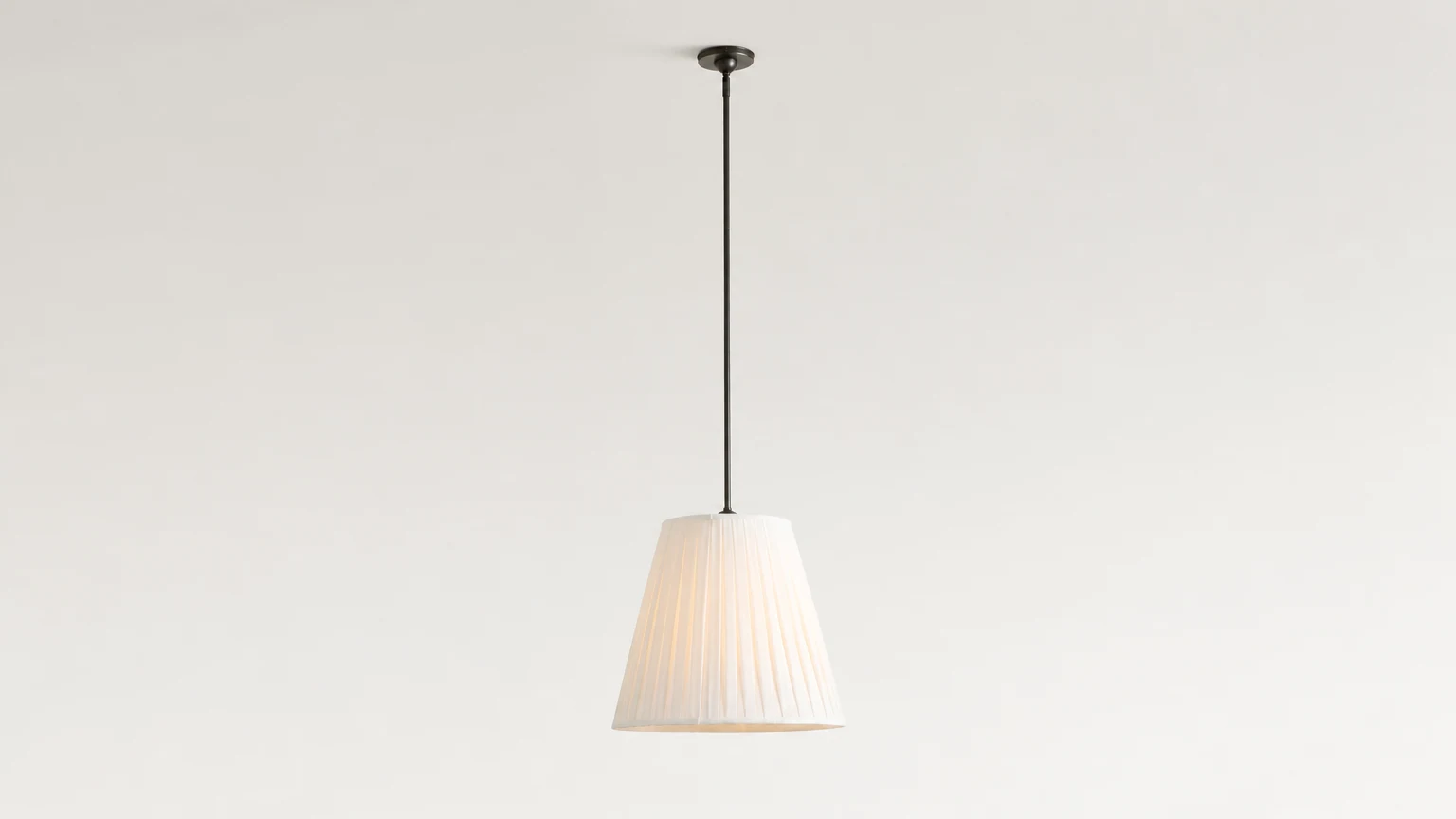 Lampa wisząca z plisowanej tkaniny Luvora pokazana w ciepłym pomieszczeniu