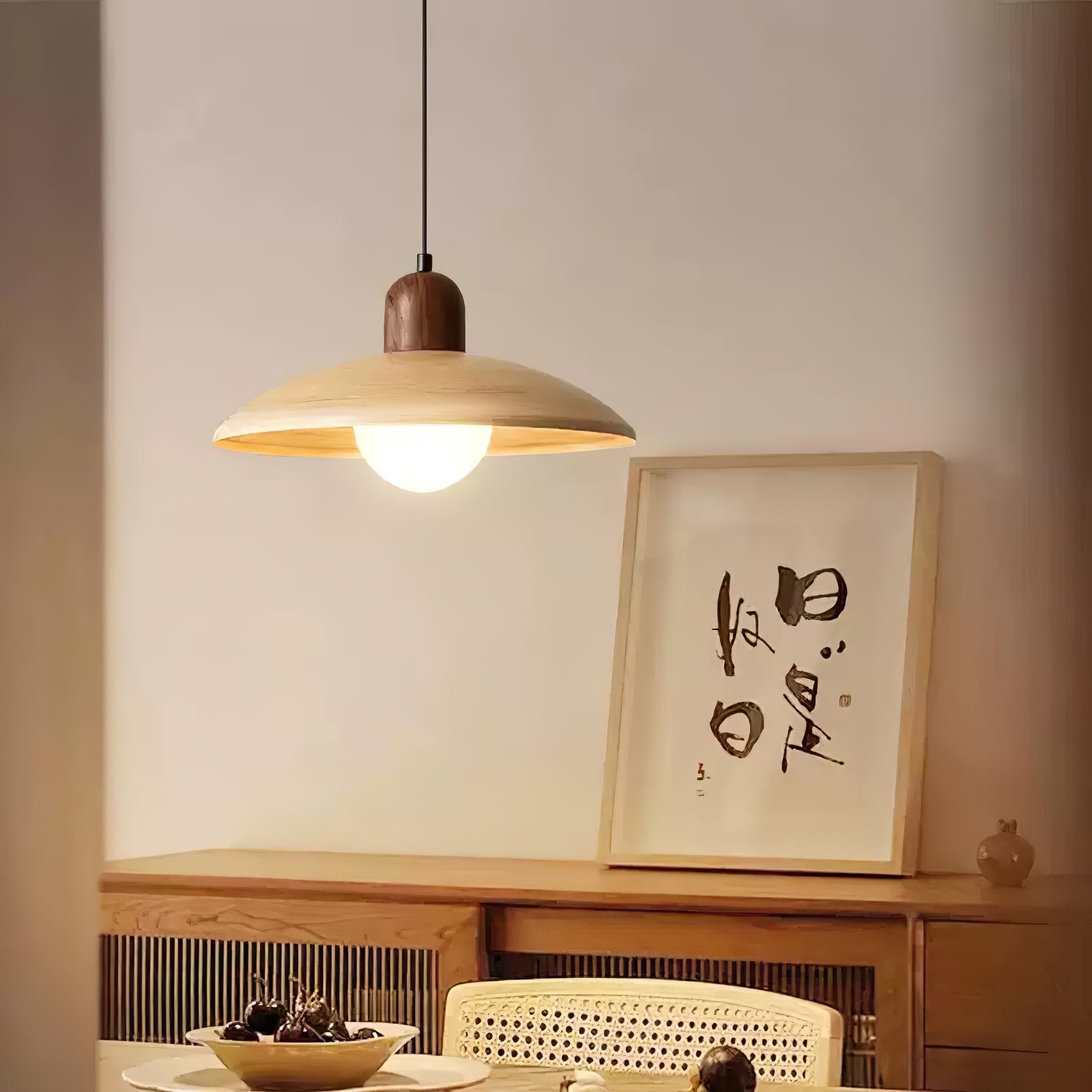 Pendant lamp lit above cabinet and wall art