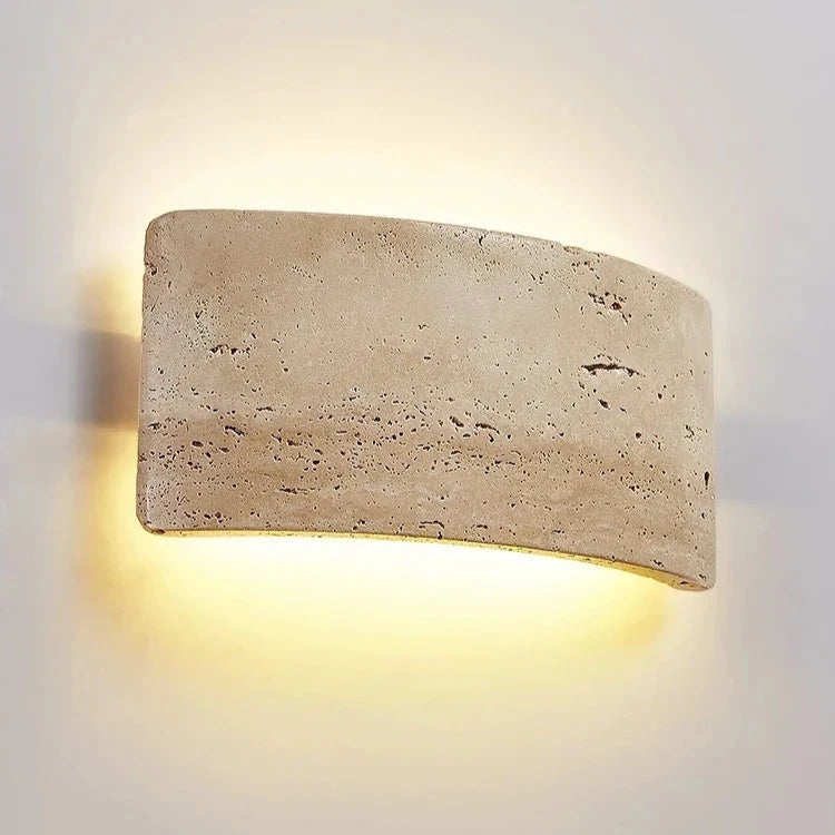 Installed close-up of travertine wall lamp with warm light