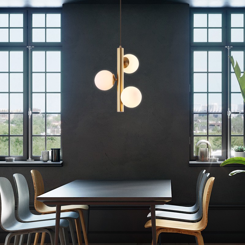 Lámpara colgante de tres bolas de cristal sobre una mesa de comedor