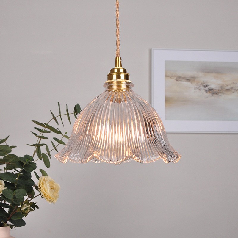 Lámpara colgante de cristal con forma de flor iluminada en un interior decorado con arte mural y flores.