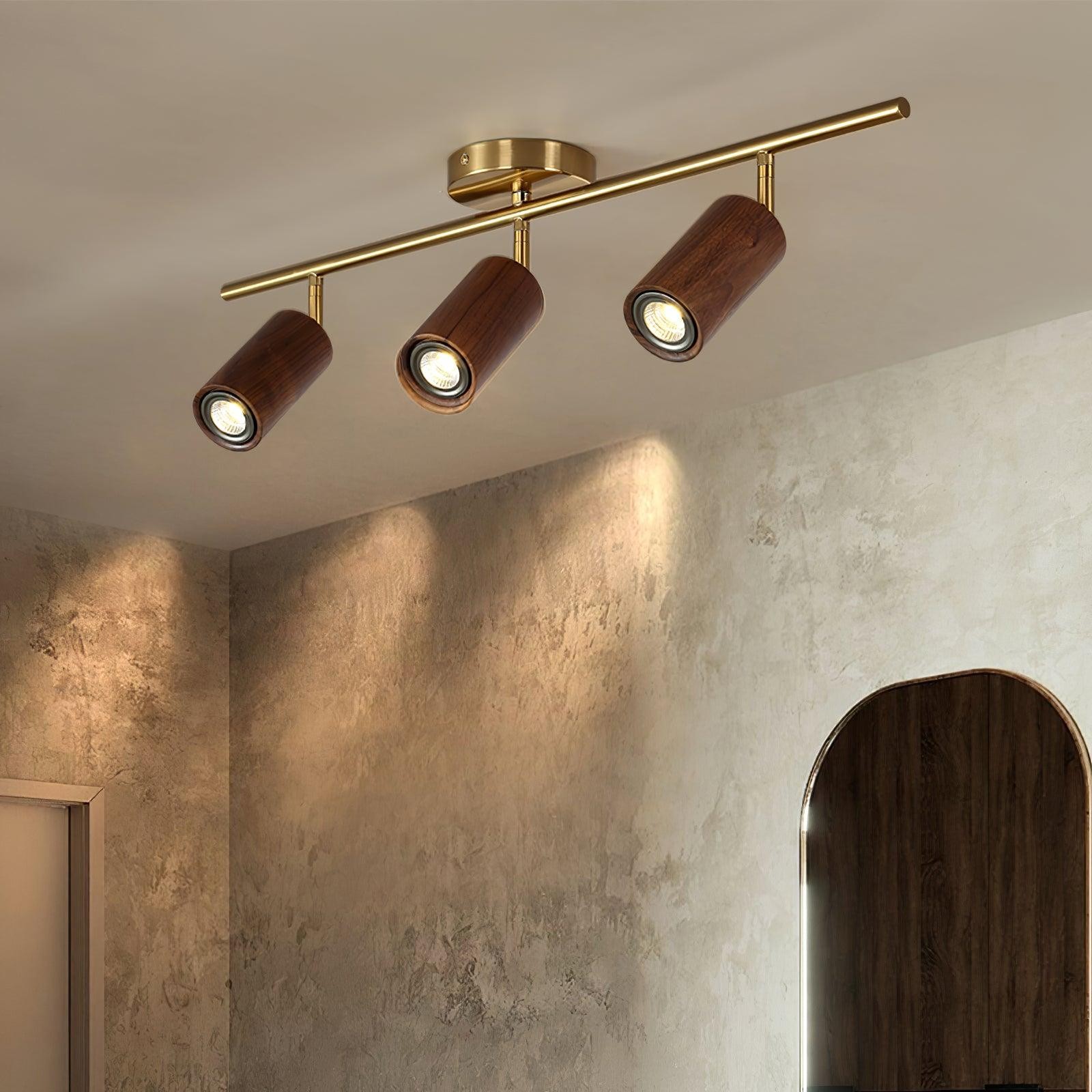 Three-head wooden track light installed in a warm wall-lit room