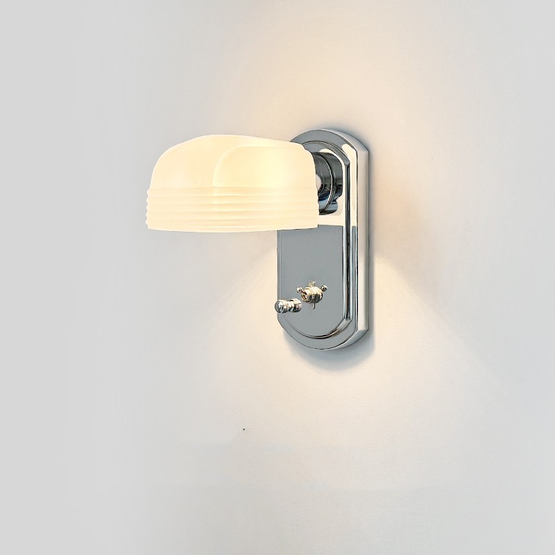Lámpara de pared de cristal blanco iluminada sobre una pared lisa.