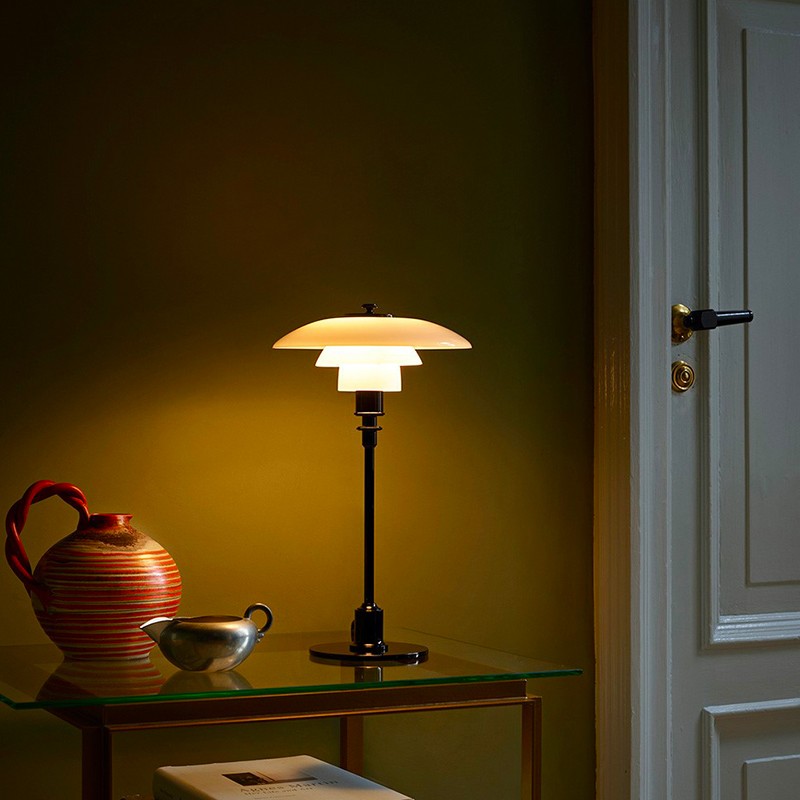 Zapalona lampa na małym stoliku w ciemniejszym pokoju