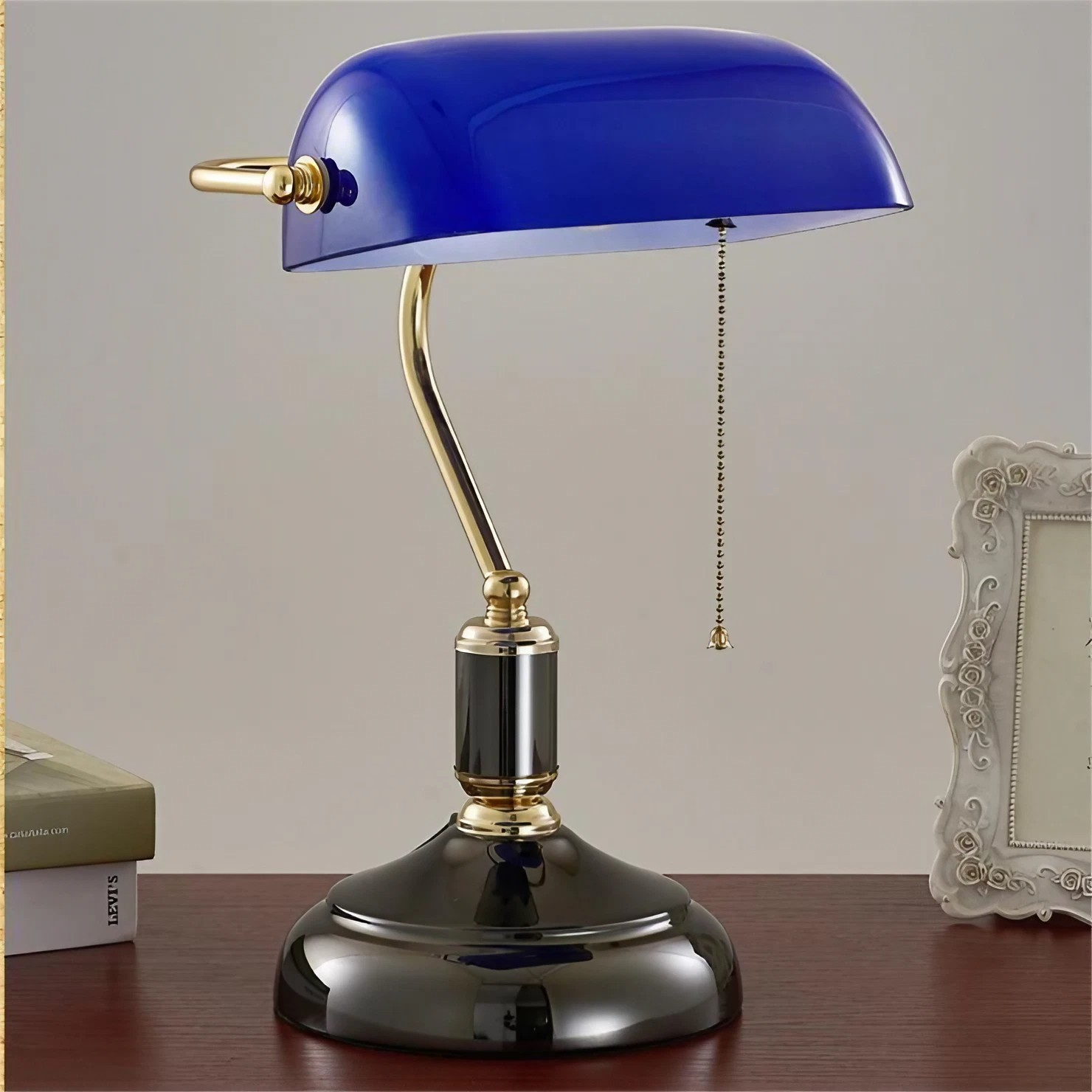 Blue banker lamp on tabletop against a neutral wall