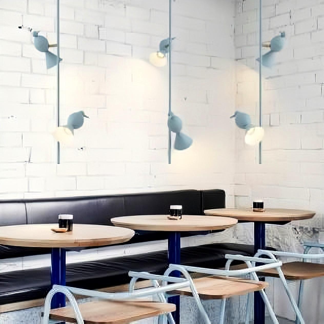 Luces colgantes con forma de pájaro azul sobre las mesas de la cafetería