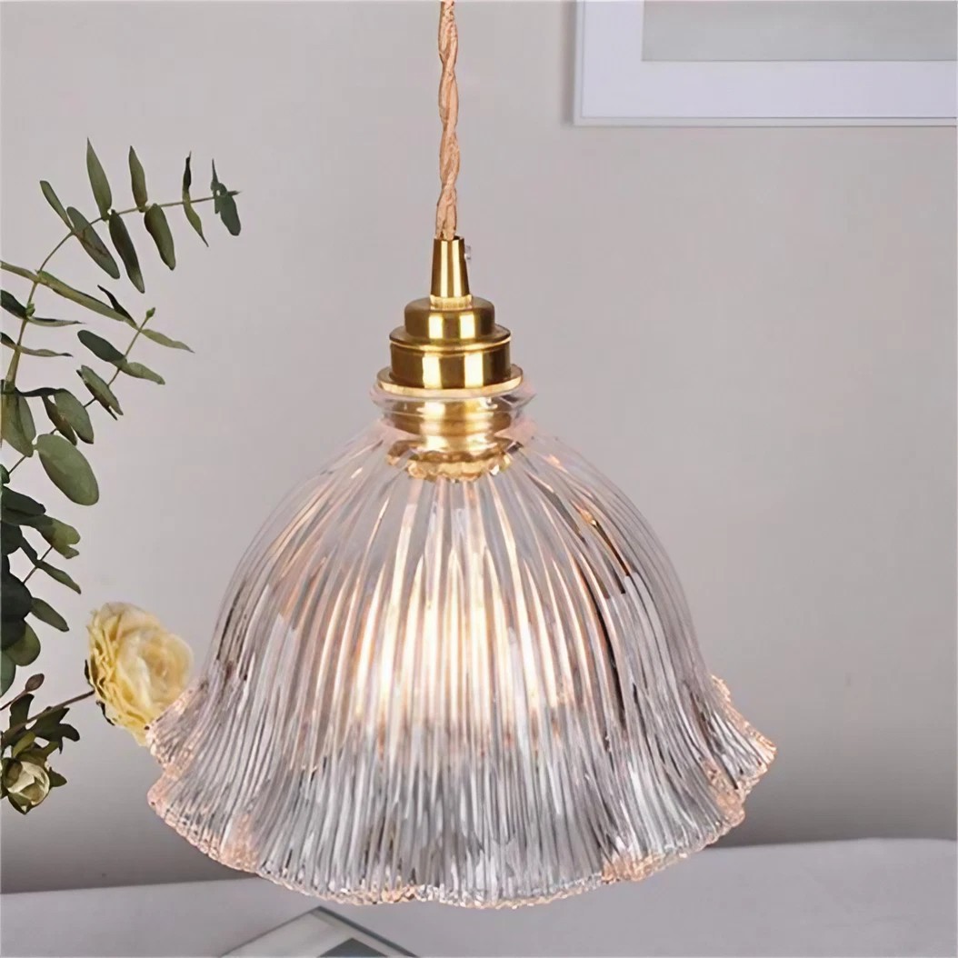 Primer plano de una escena cotidiana con una lámpara colgante de cristal transparente en forma de flor iluminada en interiores.