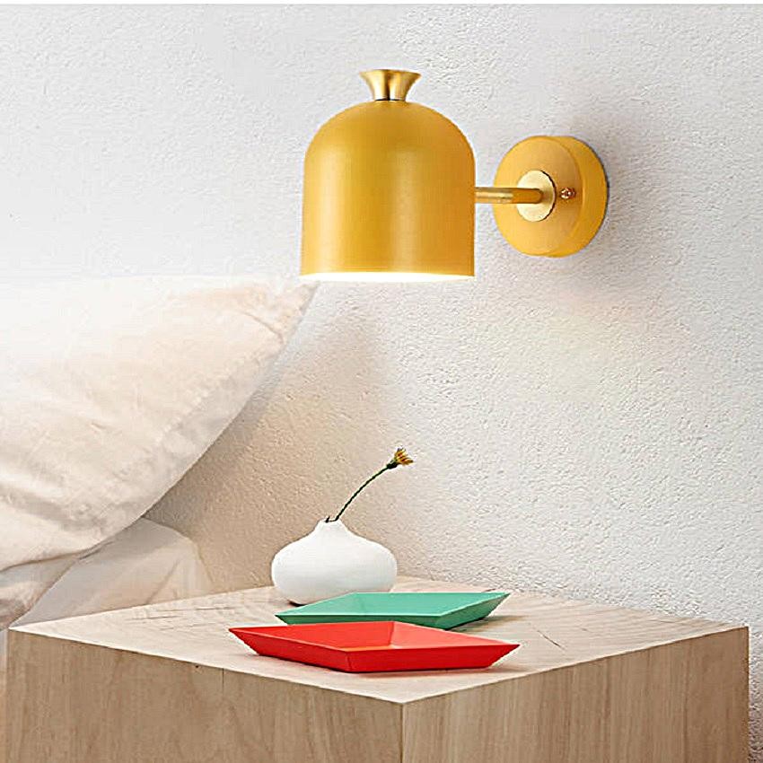Żółta lampa ścienna makaronik zapalona w pobliżu stolika nocnego