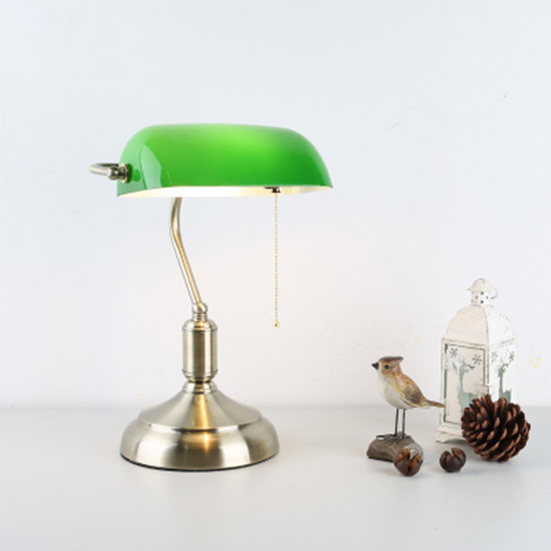 Green banker lamp on a light tabletop with small decor