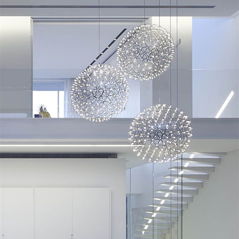 Diverse lampade a sospensione a forma di palla da fuoco in una tromba delle scale luminosa