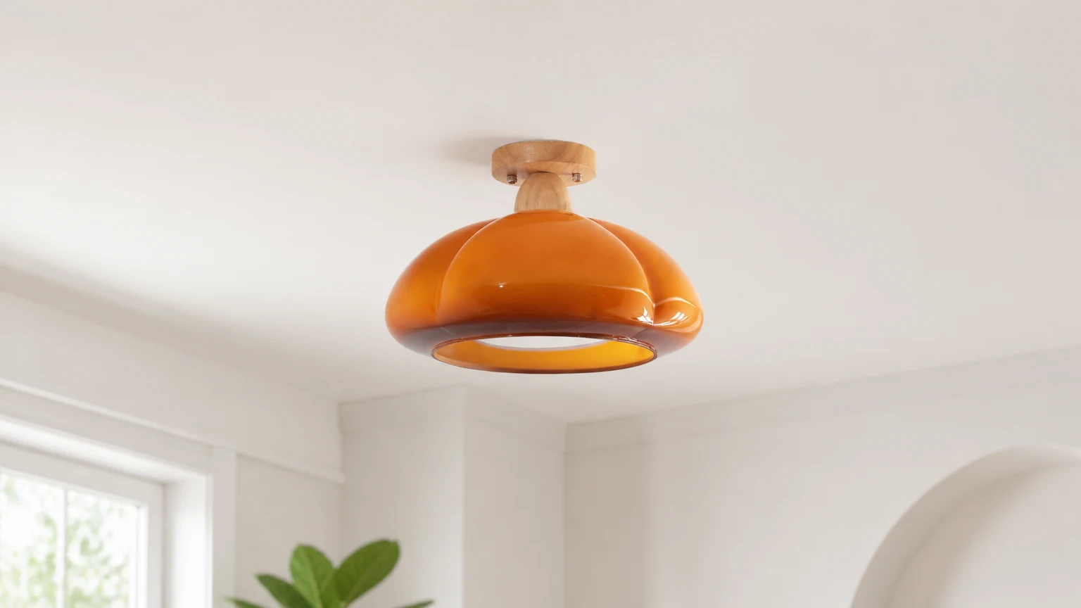 Suspension lumineuse en verre en forme de citrouille installée dans un intérieur chaleureux